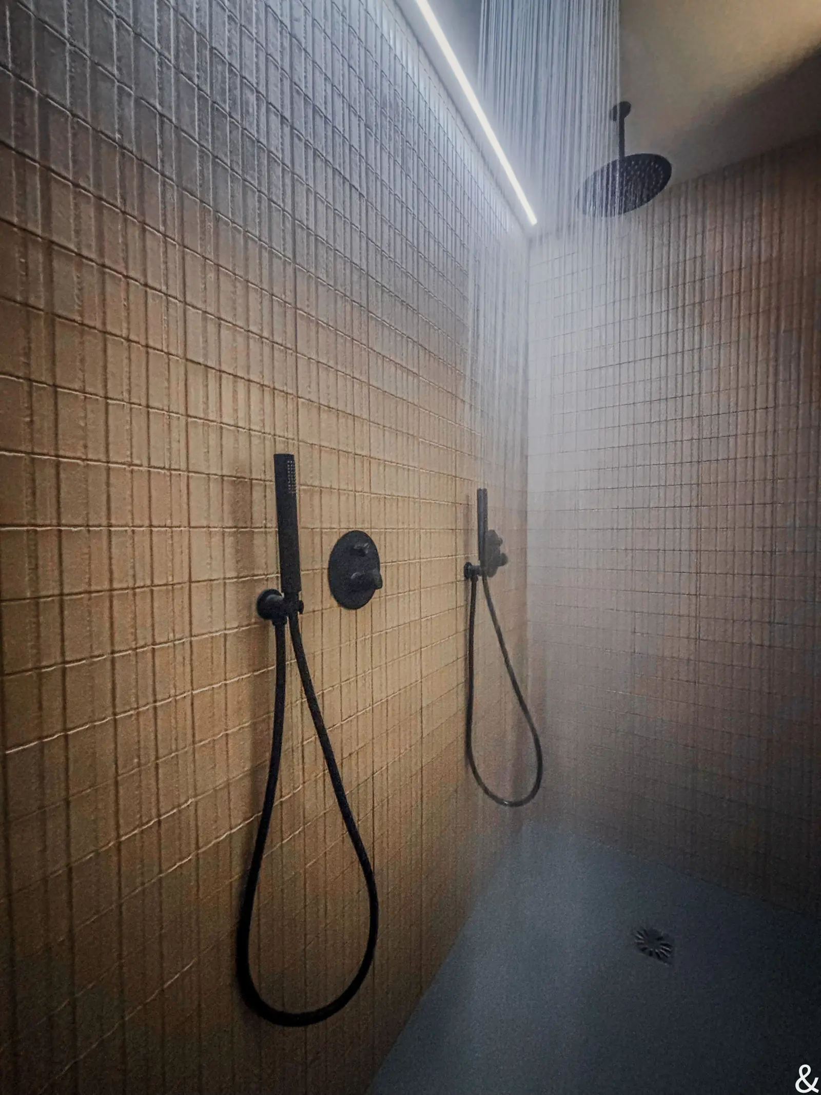 La douche, deux pommeaux côte à côte sur le carrelage clair