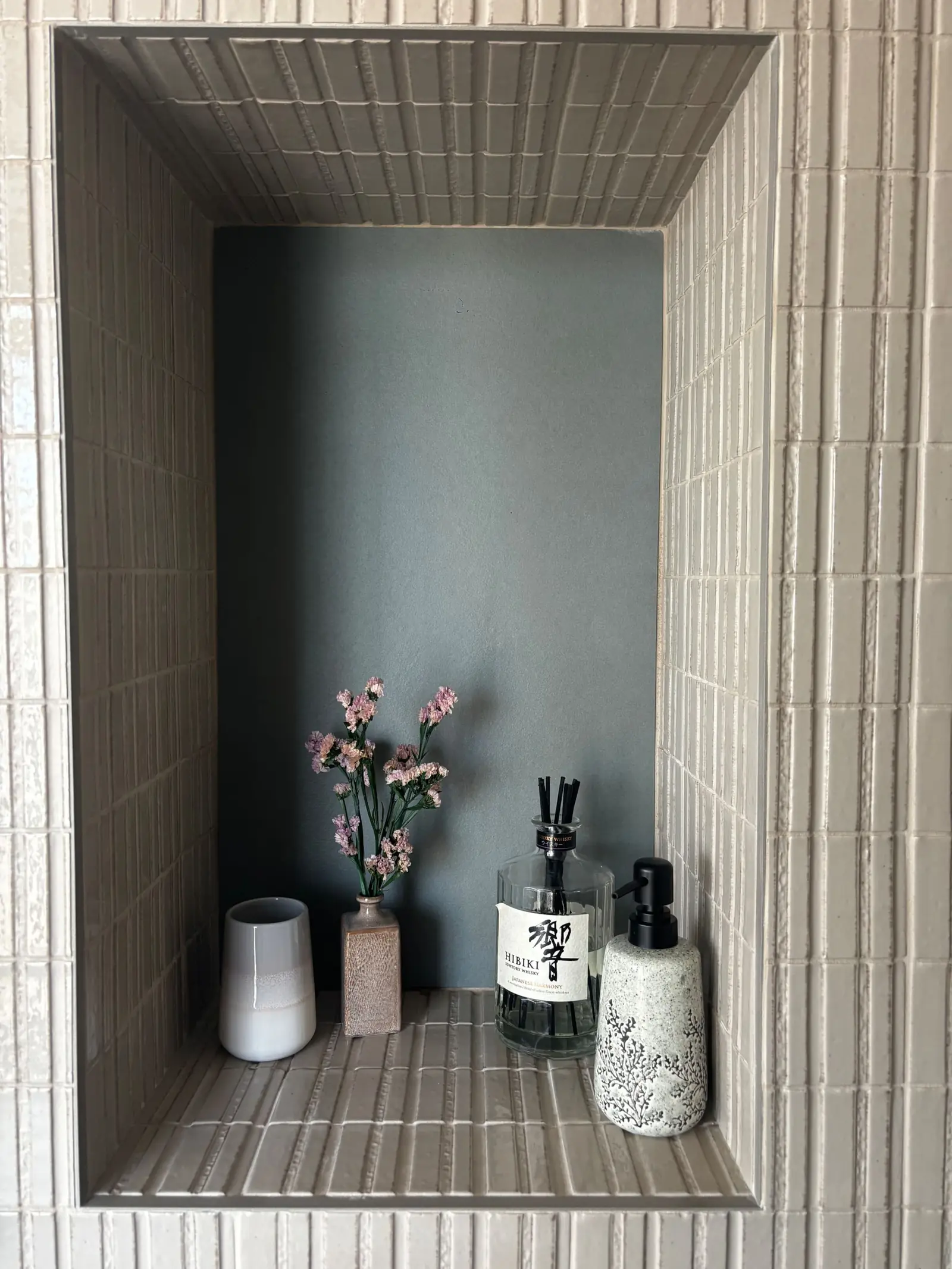 Fleurs roses dans un vase, mur bleu nuit et carrelage blanc